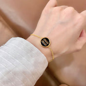 MIUMIU 26S LOGO ROUND BRACELET IN BLACK ENAMEL AND GOLD TONE METAL 631809