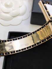 CHANEL 26S CHANEL LOGO ENAMEL CUFF BRACELET WITH BLACK TRIM IN GOLD METAL 630835